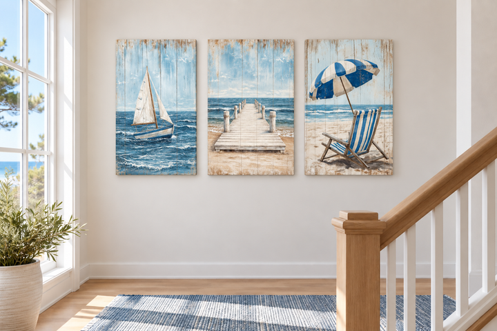 Set of 3 coastal canvas prints featuring a sailboat, a wooden pier, and a beach chair with umbrella.