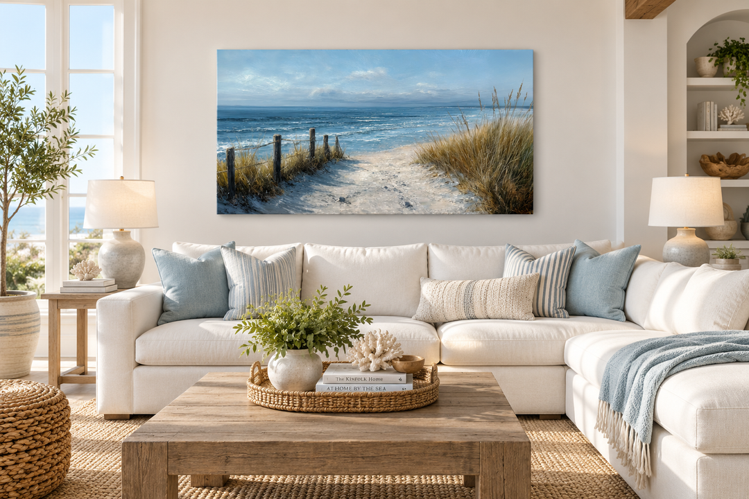 Horizontal coastal beach wall art canvas print of a sandy path to the ocean above a white sofa.