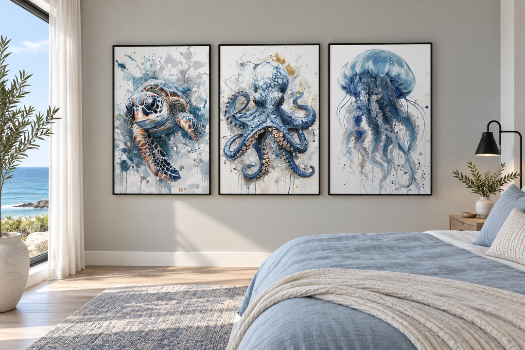 Three framed watercolor prints of a sea turtle, octopus, and jellyfish above a bed in a beach house.