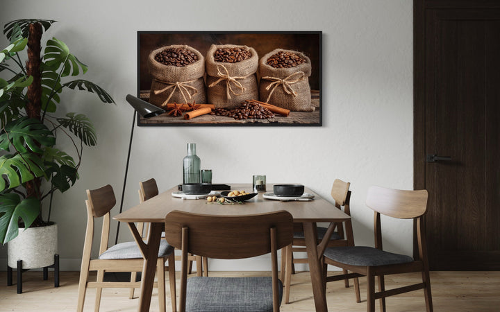 Coffee in burlap bags and cinnamon sticks framed canvas wall art above a dining table.