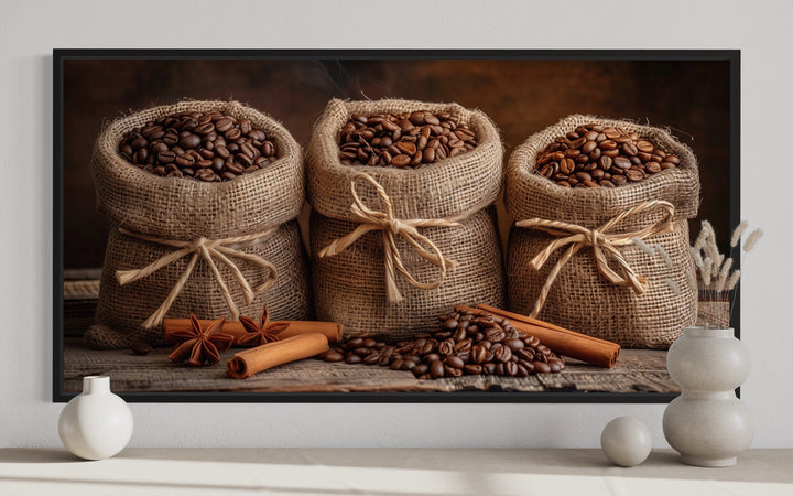 Framed canvas wall art of coffee beans in burlap bags with cinnamon sticks and star anise.