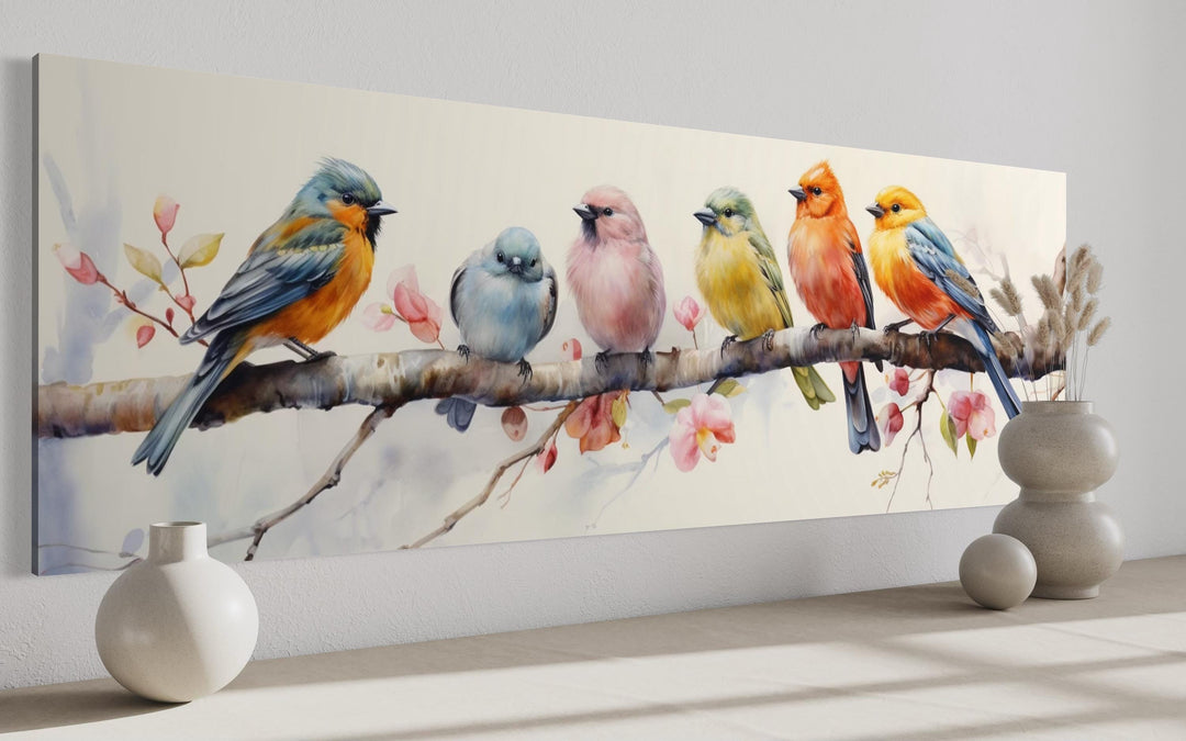 Long horizontal wall art of six colorful birds perched on a branch with pink blossoms.