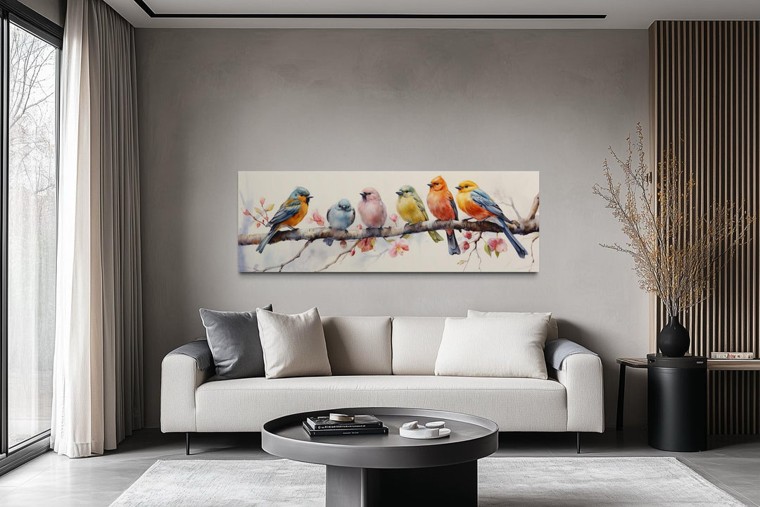 Colorful birds on a branch long horizontal wall art above a modern sofa in a living room.