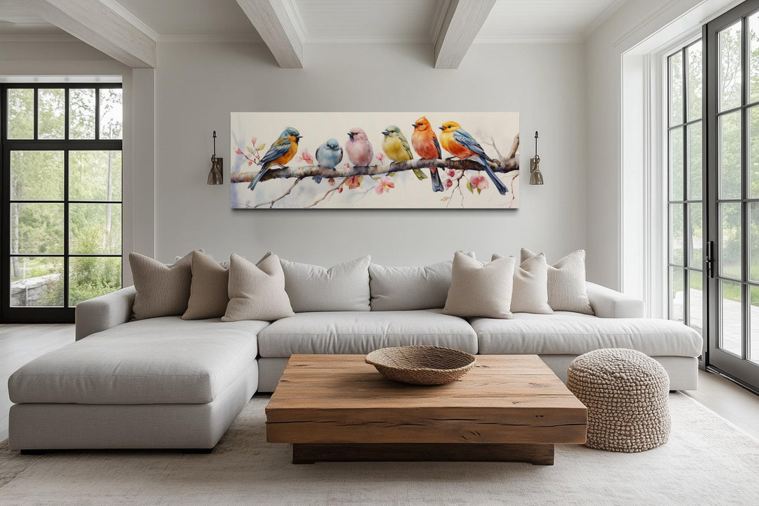 Colorful birds on a branch long horizontal wall art displayed above a sofa in a modern living room.