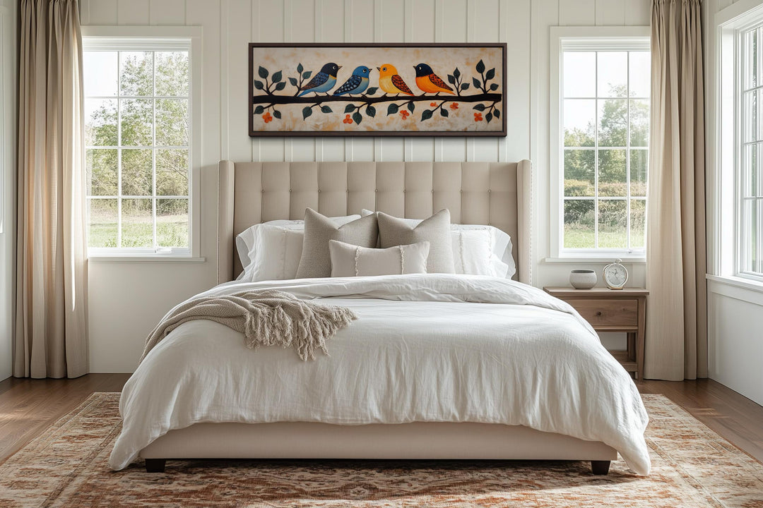 Folk style long narrow canvas print of colorful birds on a branch hanging above a bed.