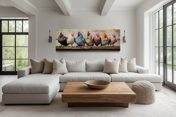Panoramic farmhouse canvas art featuring seven colorful chickens on a fence above a modern sofa.