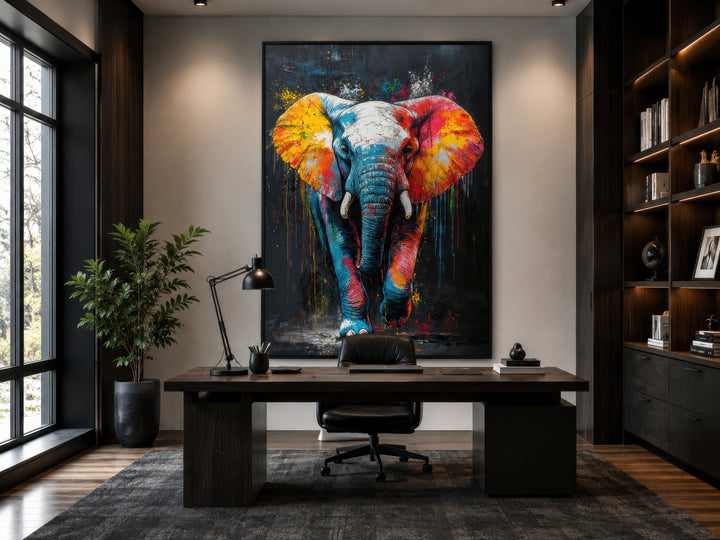 Colorful graffiti elephant framed canvas wall art hanging above a dark wood desk in a modern office.