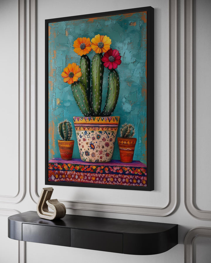 Colorful Mexican blooming cactus framed canvas wall art hanging above a black console table.