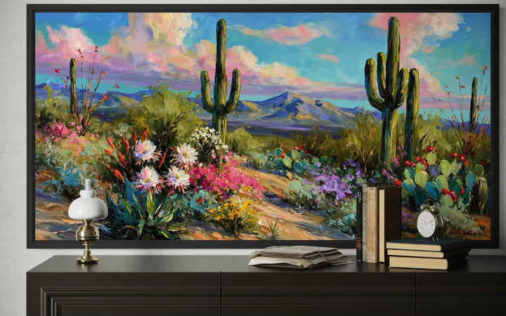 Colorful saguaro cactus and wildflower desert landscape painting in a black frame.