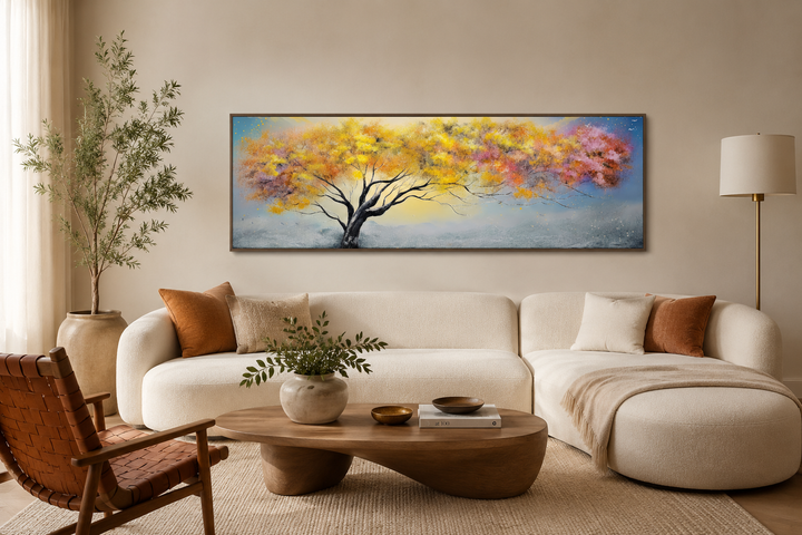 Horizontal framed canvas wall art of a colorful tree with pink, blue, and yellow leaves over a sofa.