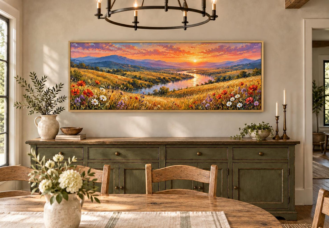 Panoramic canvas art of a wildflower meadow and river sunset above a green sideboard.
