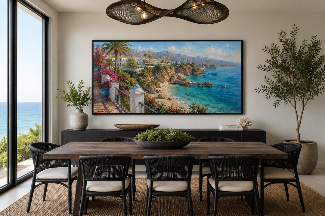 Framed canvas wall art of a sun-drenched Mediterranean coastal village above a dining table.