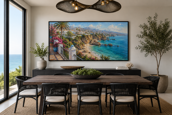 Framed canvas wall art of a sun-drenched Mediterranean coastal village above a dining table.