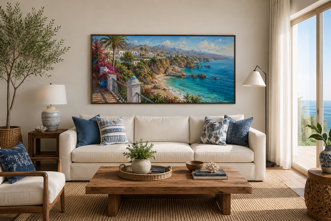 Framed canvas wall art of a Mediterranean coastal village above a white sofa in a coastal room.
