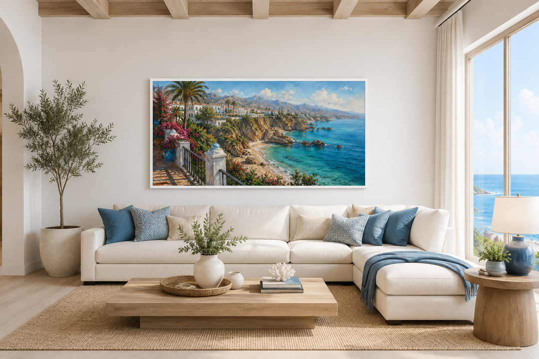 Framed canvas wall art of a Costa Del Sol Mediterranean coastal village above a white sofa.