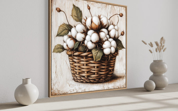 Framed canvas wall art of cotton bolls in a wicker basket for rustic farmhouse decor.