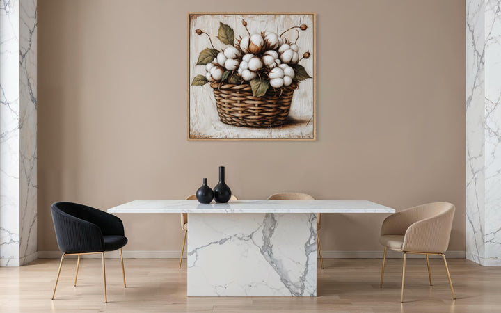 Cotton bolls in a wicker basket canvas wall art hanging above a modern marble dining table.