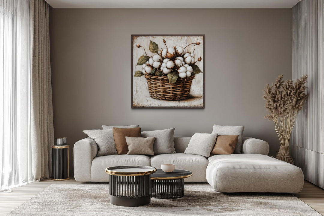 Cotton bolls in a wicker basket canvas wall art displayed above a modern sofa in a neutral room.