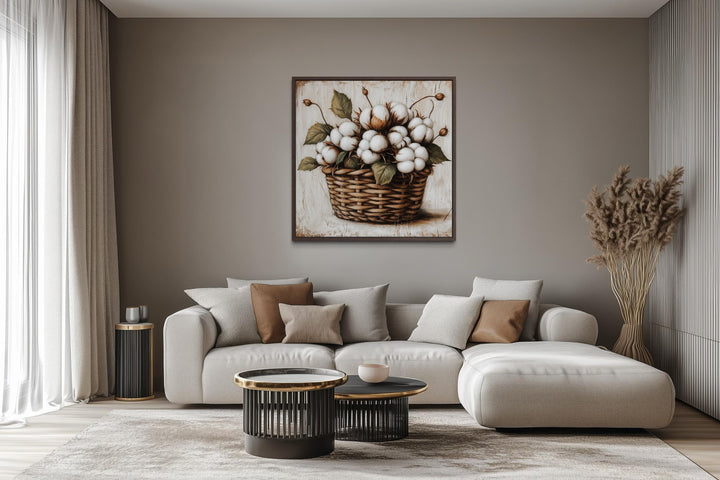 Cotton bolls in a wicker basket canvas wall art displayed above a modern sofa in a neutral room.