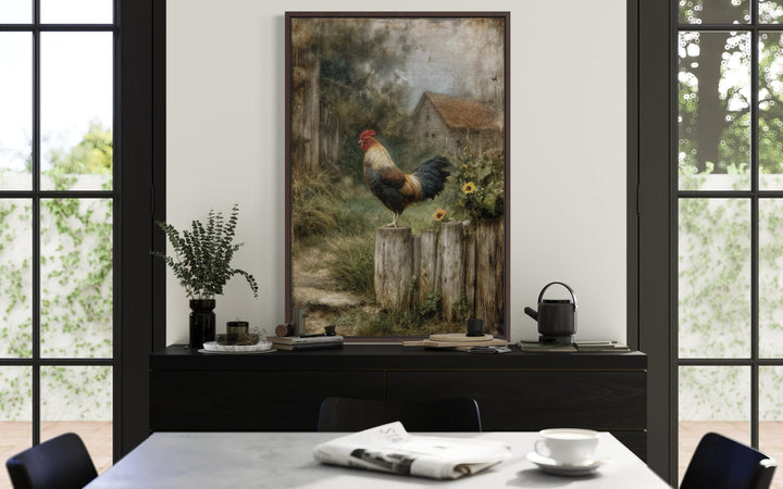 A framed canvas print of a rooster on a wooden fence with a rustic barn landscape in the background.
