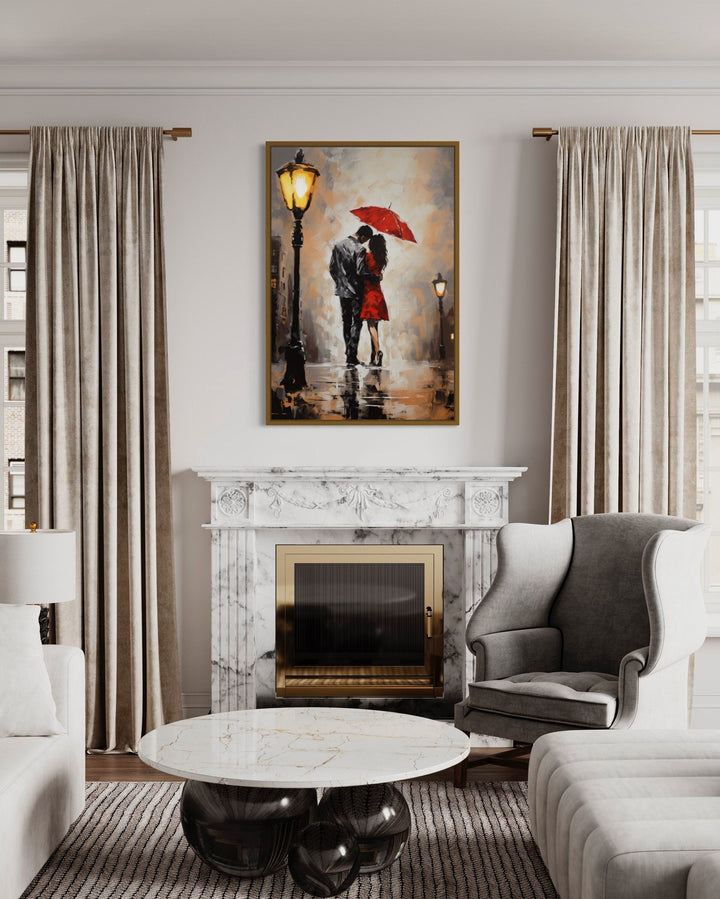 Framed canvas wall art of a couple under a red umbrella in the rain above a marble fireplace.