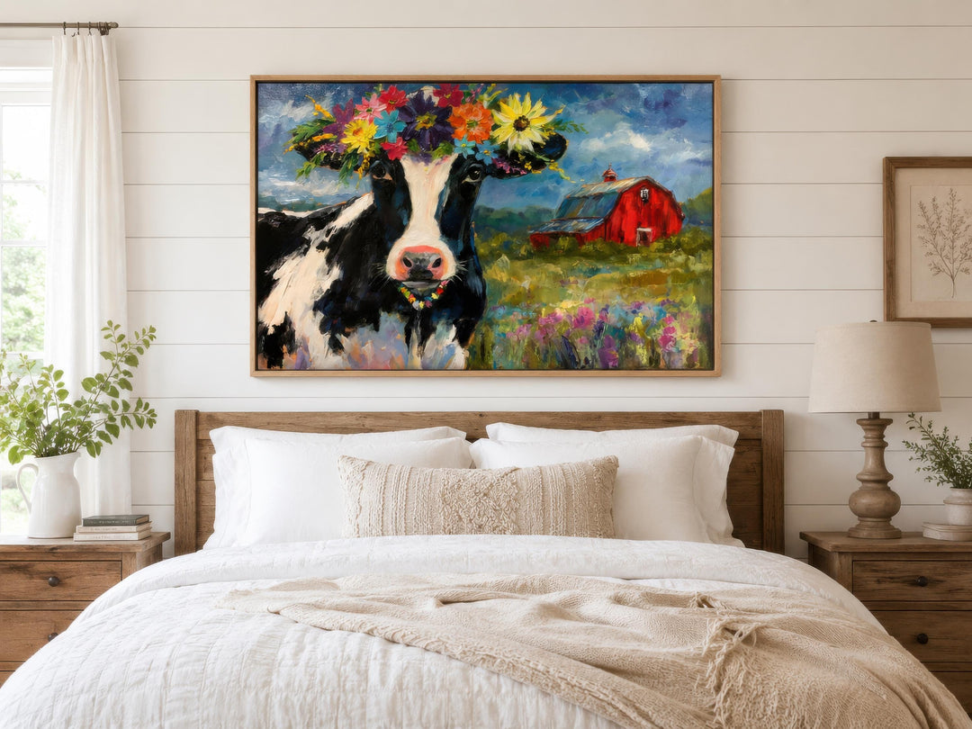 Whimsical canvas wall art of a cow with a flower crown hanging above a bed in a farmhouse bedroom.