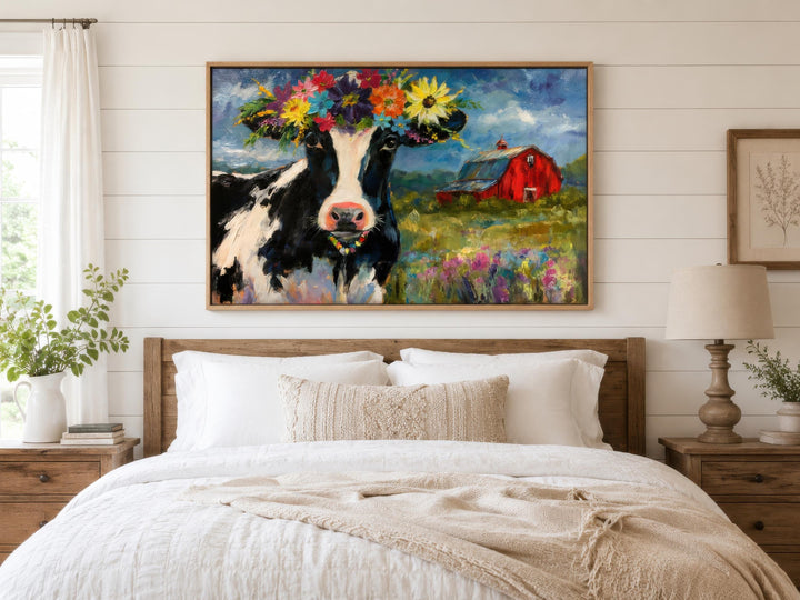 Whimsical canvas wall art of a cow with a flower crown hanging above a bed in a farmhouse bedroom.