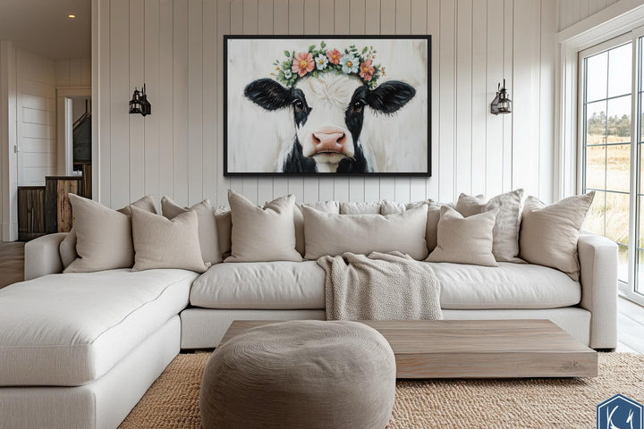 Cow with floral wreath canvas wall art hanging above a neutral sectional sofa in a farmhouse room.