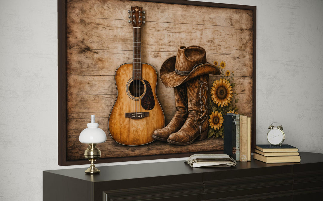 Rustic canvas wall art featuring a guitar, cowboy boots, hat, and sunflowers on a wooden background.