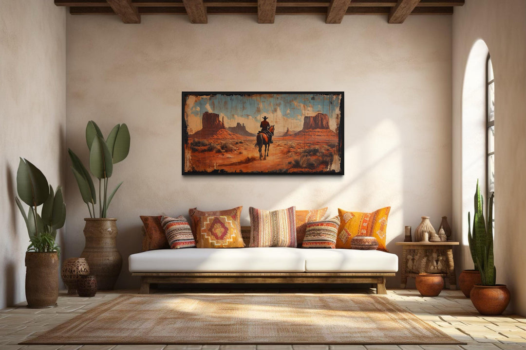 Cowboy riding a horse in Monument Valley framed canvas wall art in a rustic living room.