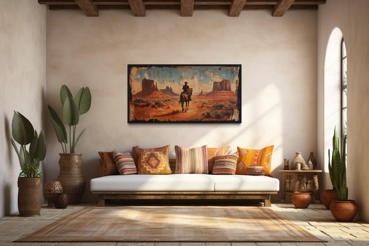Cowboy riding a horse in Monument Valley framed canvas wall art in a rustic living room.