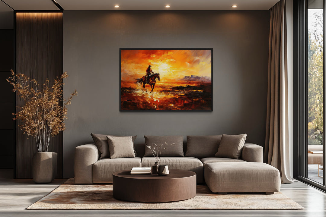 Cowboy riding a horse in the desert at sunset canvas art hanging above a modern sofa in a living room