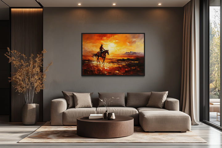 Cowboy riding a horse in the desert at sunset canvas art hanging above a modern sofa in a living room