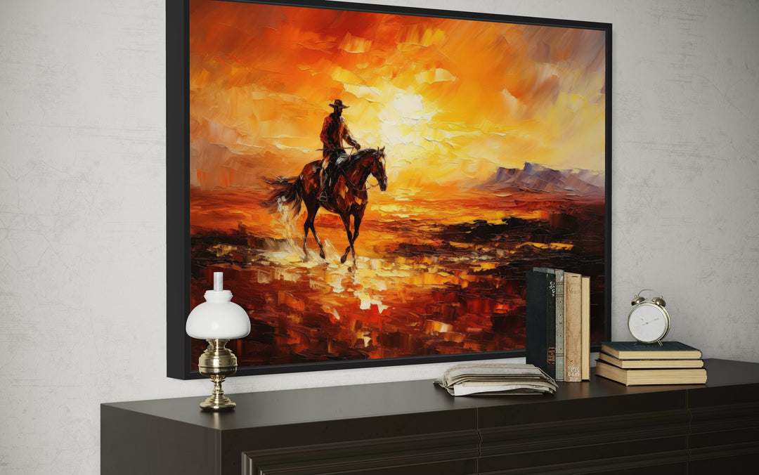 Cowboy riding a horse in the desert at sunset oil painting style canvas art on a dark dresser.