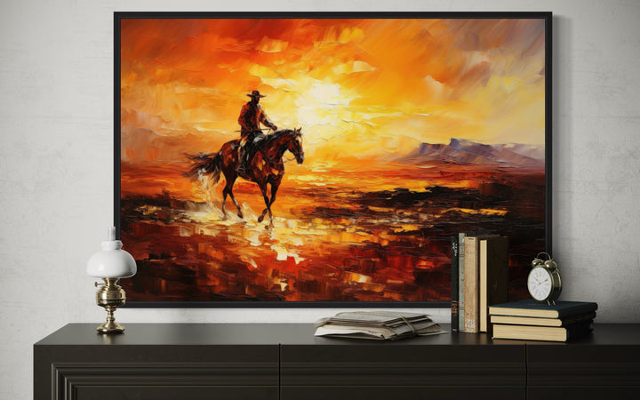 Oil painting of a cowboy riding a horse through a desert at sunset, displayed in a black frame.
