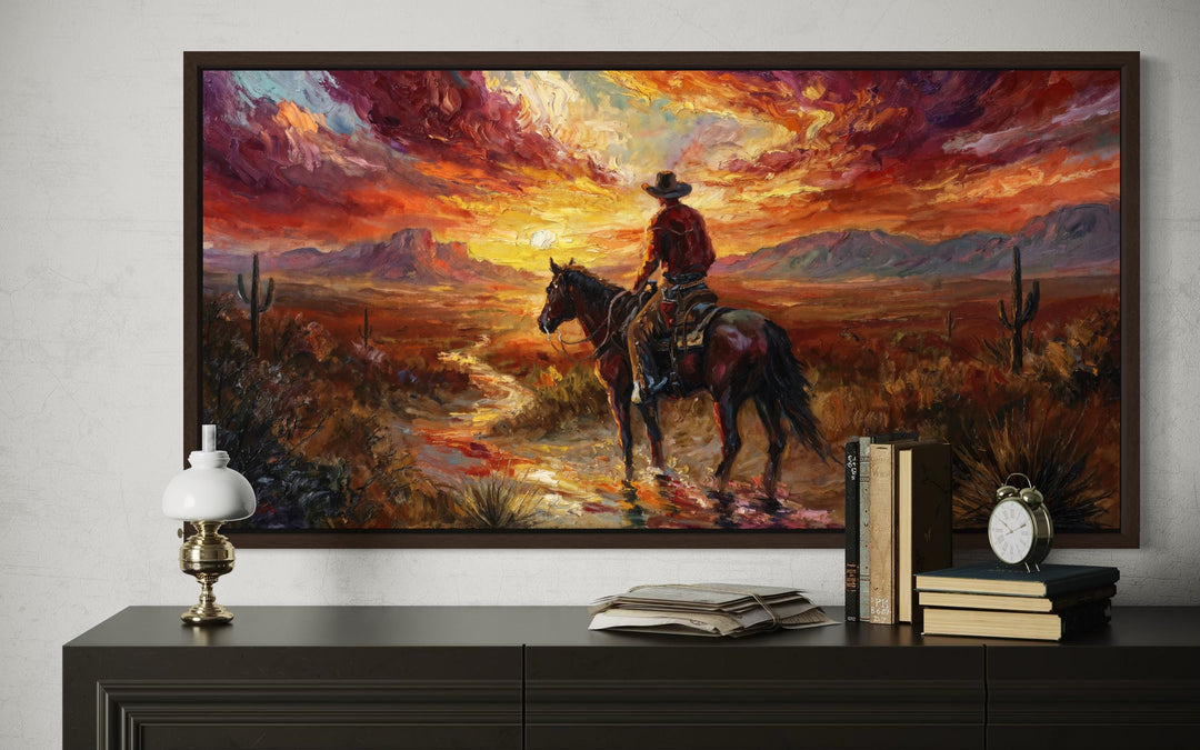 Framed canvas art of a cowboy on horseback riding through a desert at sunset with vibrant colors.