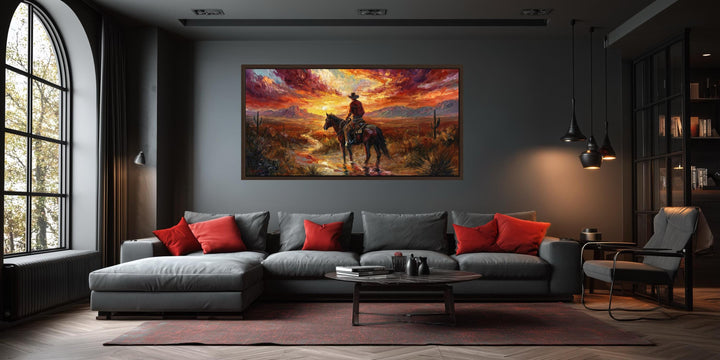 A wide horizontal canvas of a cowboy riding through a desert at sunset in a modern living room.