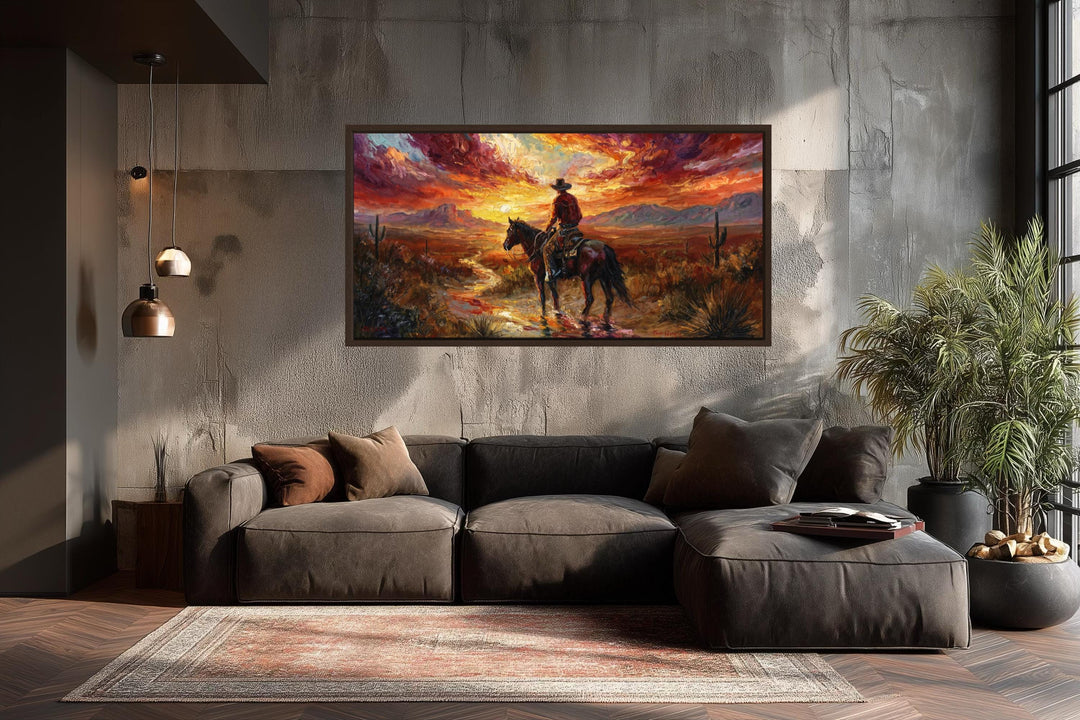 A framed canvas of a cowboy riding through a desert sunset hangs above a modern brown sectional sofa.