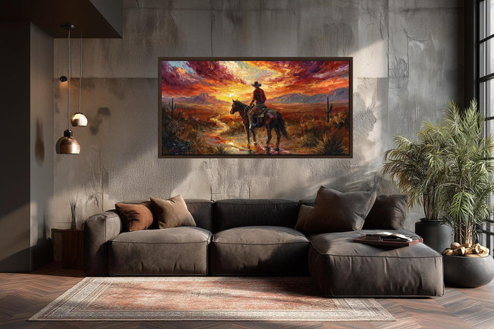 A framed canvas of a cowboy riding through a desert sunset hangs above a modern brown sectional sofa.