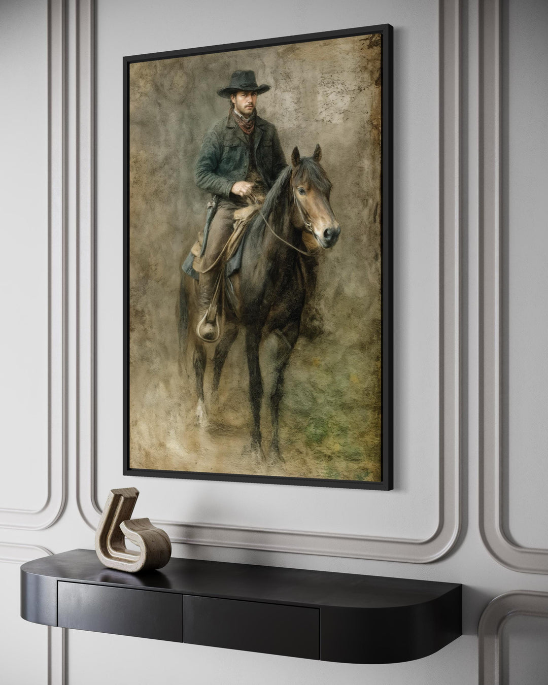 A rustic western canvas print of a cowboy on horseback in a black frame above a modern console.