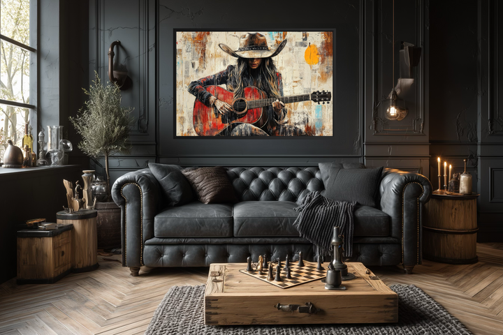 Framed canvas wall art of a cowgirl playing a red guitar in a dark, rustic living room.