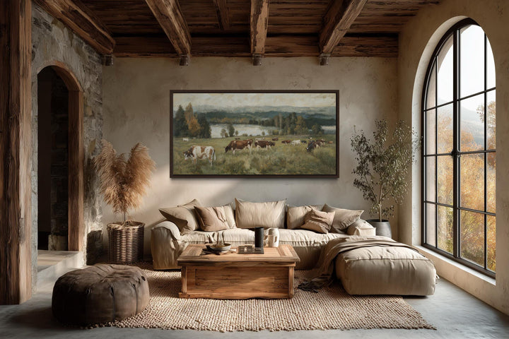 A large horizontal canvas painting of cows grazing in a pasture hangs in a rustic farmhouse room.