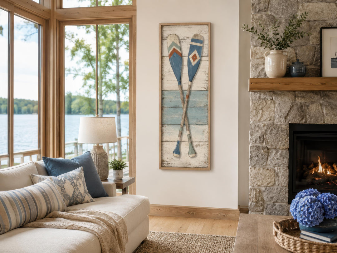 Tall narrow canvas wall art featuring two crossed weathered oars in blue and cream on a white wall.