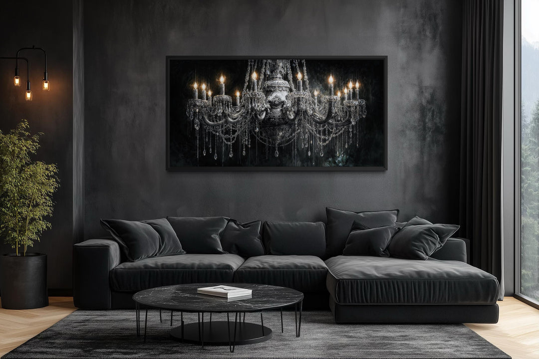 Large horizontal canvas wall art of a crystal chandelier on a dark wall above a black sofa.
