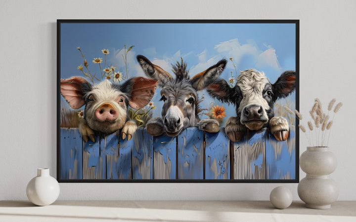 Framed canvas art of a pig, donkey, and baby cow peeking over a rustic blue wooden fence.