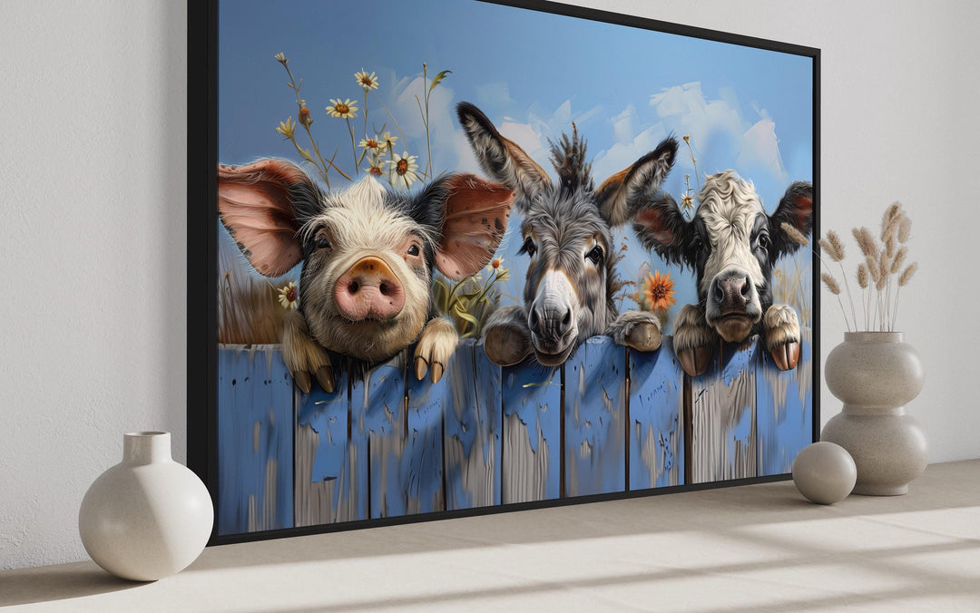 Framed canvas art of a pig, donkey, and baby cow looking over a rustic blue wooden fence.