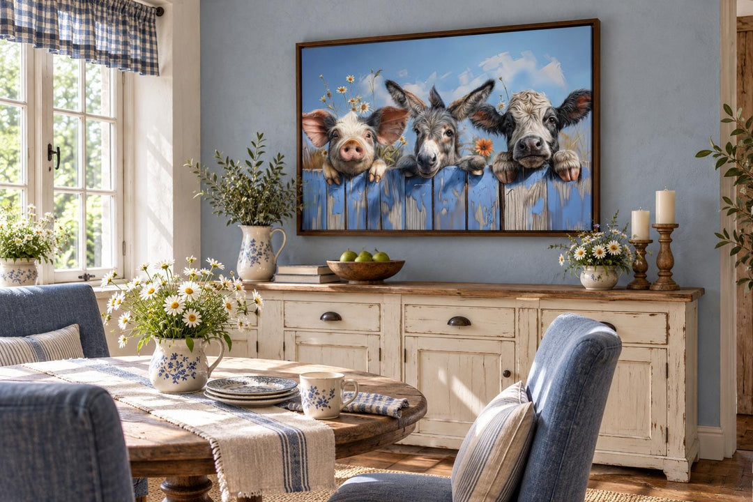 Framed canvas wall art of a donkey, pig, and baby cow looking over a blue wooden fence with daisies.