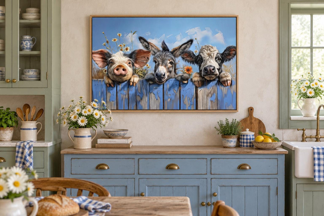 Framed canvas art of a pig, donkey, and baby cow looking over a blue fence in a farmhouse kitchen.
