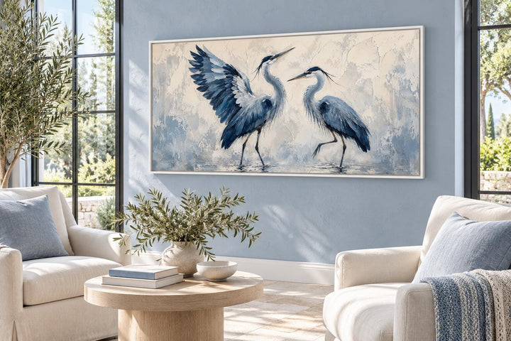 Dancing Blue Herons navy blue and cream canvas wall art above a sofa in a coastal living room.