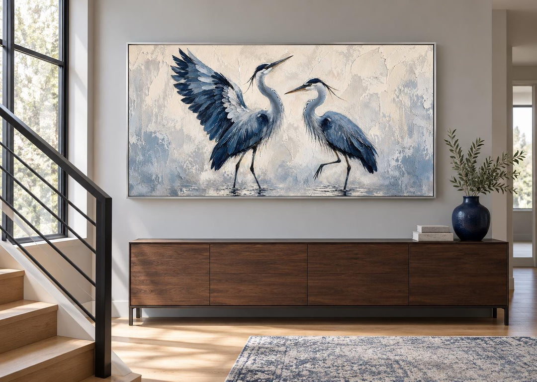 Dancing Blue Herons canvas wall art featuring two blue birds on a cream background above a sideboard.